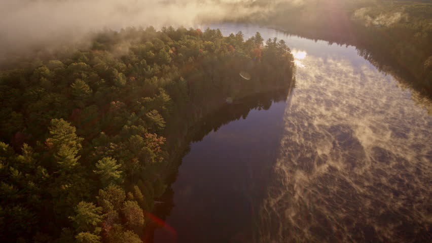 Drone captures ethereal mist lifting from water at daybreak.