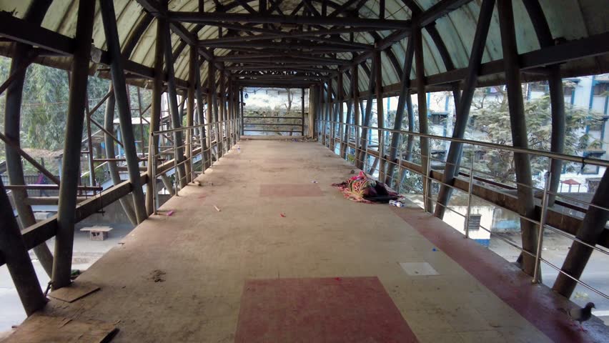 A homeless person sleeping on the side of a pedestrian crossing bridge early in the morning in Powai, Mumbai, India