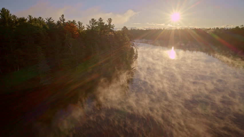Aerial drone footage of gentle mist moving upward from water at daybreak.