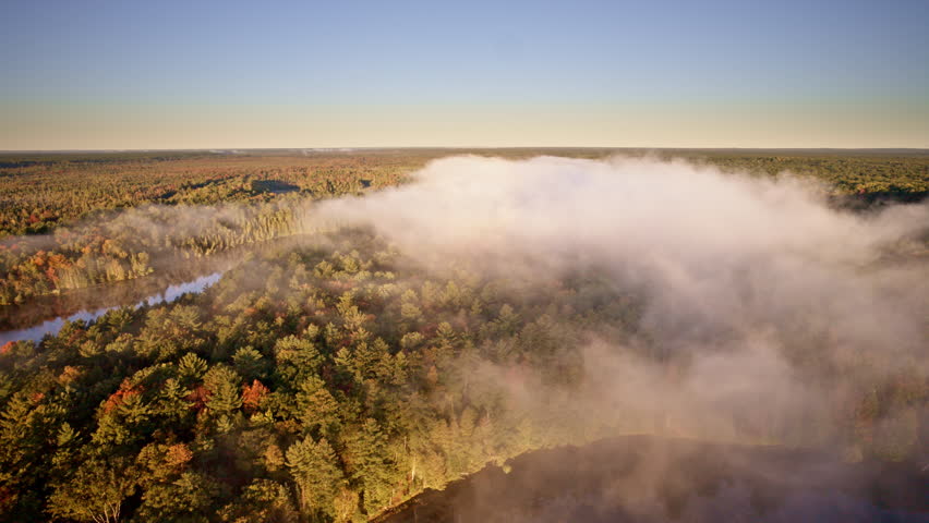 Aerial drone pass capturing haze drifting upward from water at daybreak.