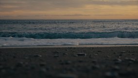 Soft ocean wave curls onto the shore during sunset. Warm, calm light over pebbled sand with a peaceful Mediterranean horizon. - Powered by Shutterstock - Get 15% off with code: PIKWIZARD15