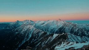 Dramatic Wide Shot of Snow-Capped Mountain Ridges at Sunset or Sunrise, with Alpenglow Illuminating the Peaks and a Cinematic Sky - Powered by Shutterstock - Get 15% off with code: PIKWIZARD15
