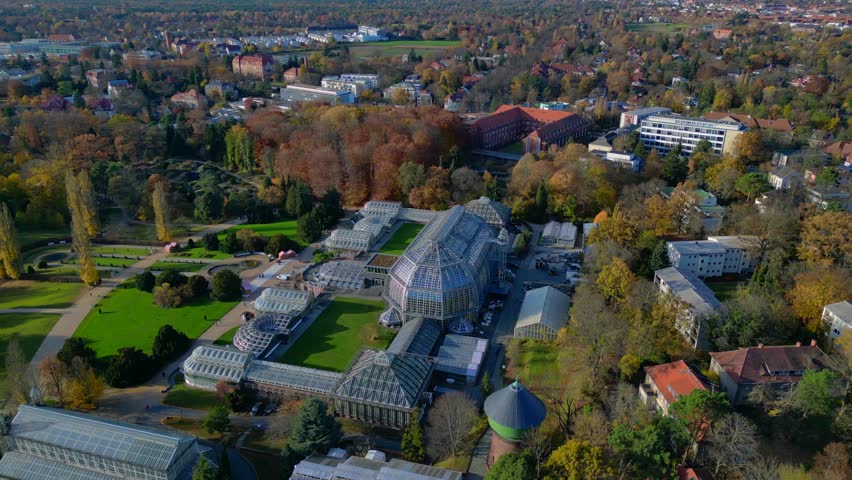 Berlin botanical garden tropical greenhouse glasshouses surrounded by autumn trees and city landscape. speed ramp hyper motion time lapse Majestic aerial view flight wide orbit overview drone