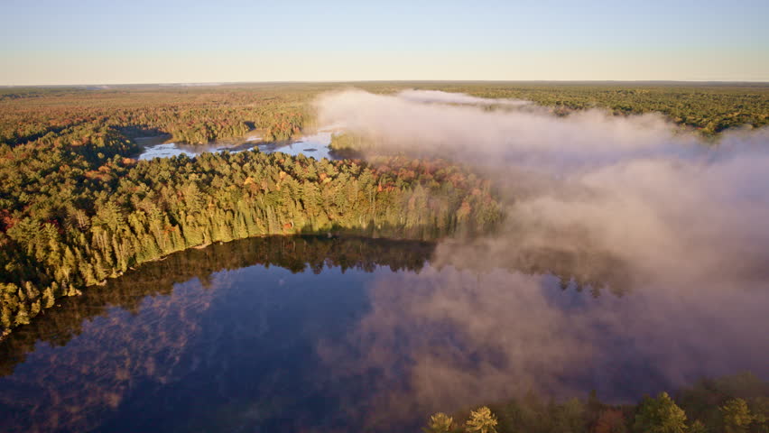 Cinematic aerial glide over misty water at dawn.