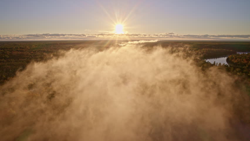 Aerial cinematic shot of dawn mist hovering over the water.