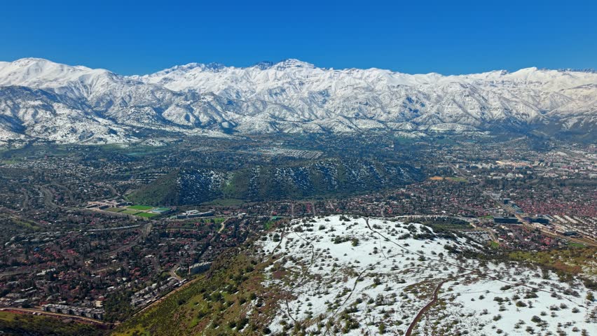 Panoramic aerial view of the eastern part of the city with the hill in the middle and snow-capped mountains in the city of Santiago, Chile.