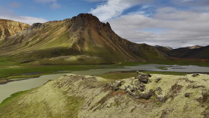 Aerial view of Landmannalaugar, where vibrant green meadows meet rugged mountains and a serene river, creating a stunning contrast, Landmannalaugar, Rangarping ytra, Iceland.