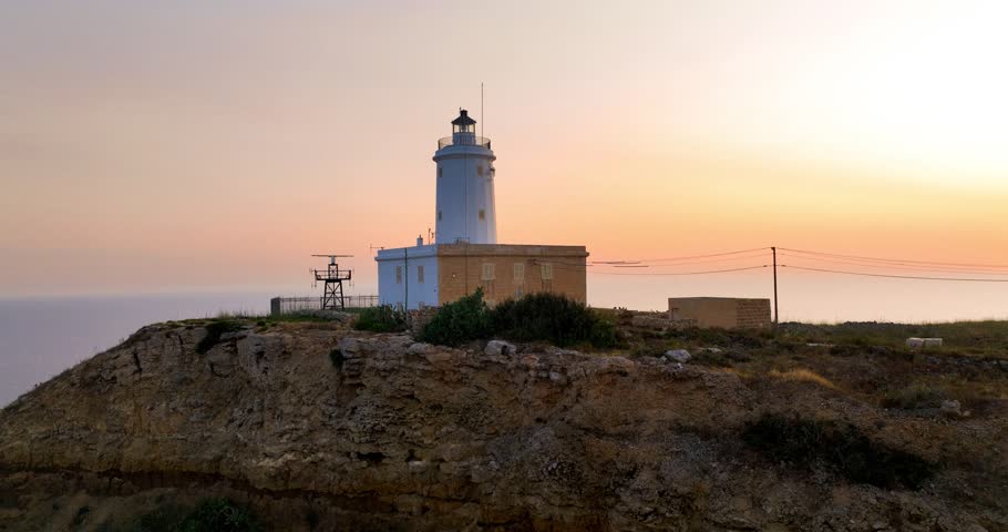 Aerial view of the white Ta' Gurdan Lighthouse perched on a cliff overlooking the calm sea under a pastel sky, Ghasr, Gozo, Malta.
