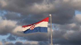  Vibrant Croatian flag with coat of arms waving in strong wind beneath a dramatic cloudy sky. Perfect for themes of patriotism, national identity, Europe, travel, and political or cultural symbolism. - Powered by Shutterstock - Get 15% off with code: PIKWIZARD15