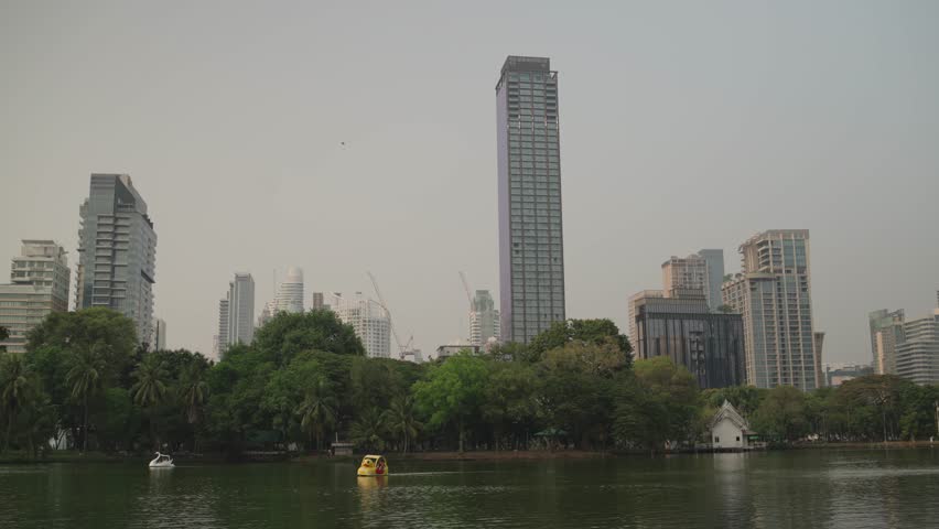 Hazy Bangkok skyline rises behind Lumphini Park