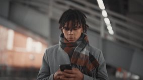 Young african american man with dreadlocks standing alone on city street in fall . Mobile gadget addiction of modern people, outdoors portrait of black male person in urban landscape in autumn day - Powered by Shutterstock - Get 15% off with code: PIKWIZARD15