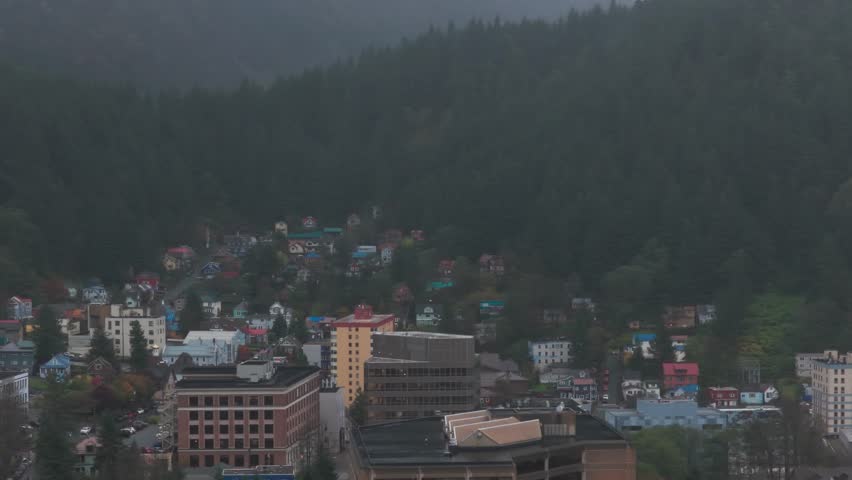 Aerial low dolly shot of government buildings and colorful homes during a rainy day in downtown Juneau, Alaska. 4K