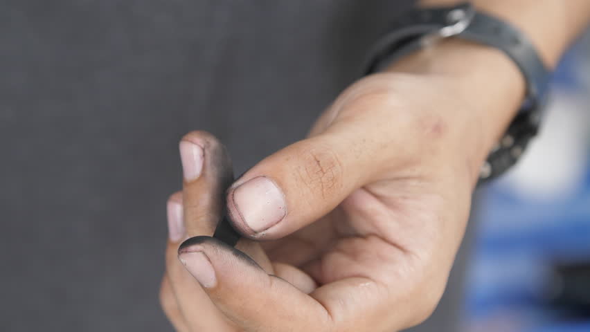 Close-up footage of a worker’s dirty fingertips holding a small black tool or part. Suitable for mechanics, repair work, craftsmanship, and manual labor concepts.