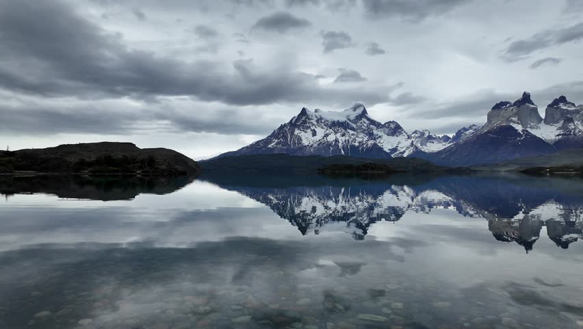 Torres del Paine, Chile: Footage of Panorama from Cordillera del Paine, mountain range in Torres del Paine National Park of Patagonia region, Chile reflected in lake under dramatic sky