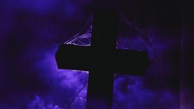 A dark cross silhouetted against eerie purple fog, with delicate spider webs visible around the edges, creating a moody, mystical atmosphere. - Powered by Shutterstock - Get 15% off with code: PIKWIZARD15