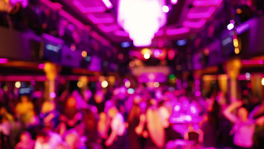 Hustling nightclub atmosphere featuring packed dance area with vivid illumination and shimmering