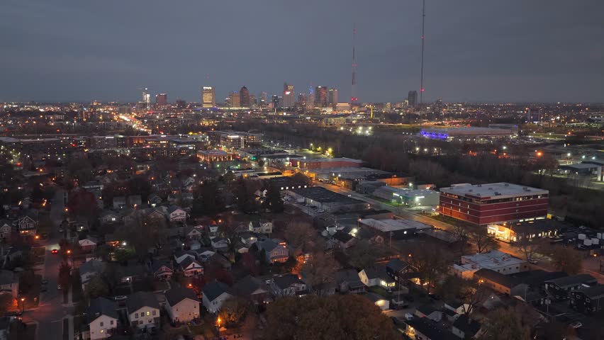Night time and darkness after blue hour drone shot of capital city Columbus, Ohio from aerial view looking towards downtown town skyscrapers, buildings, traffic lights, and glow of city life in U.S.
