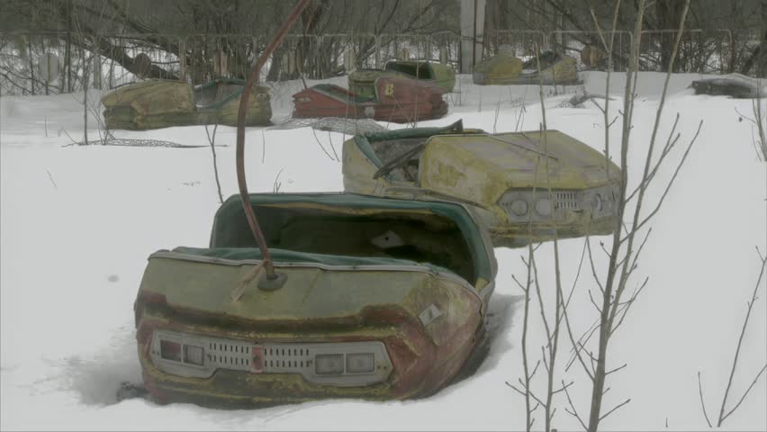 Close-up of Rusted Bumper Cars Covered in Snow in the Abandoned Pripyat Amusement. A low-angle close-up view of severely rusted and snow-covered bumper cars (autodrome) in the abandoned amusement park