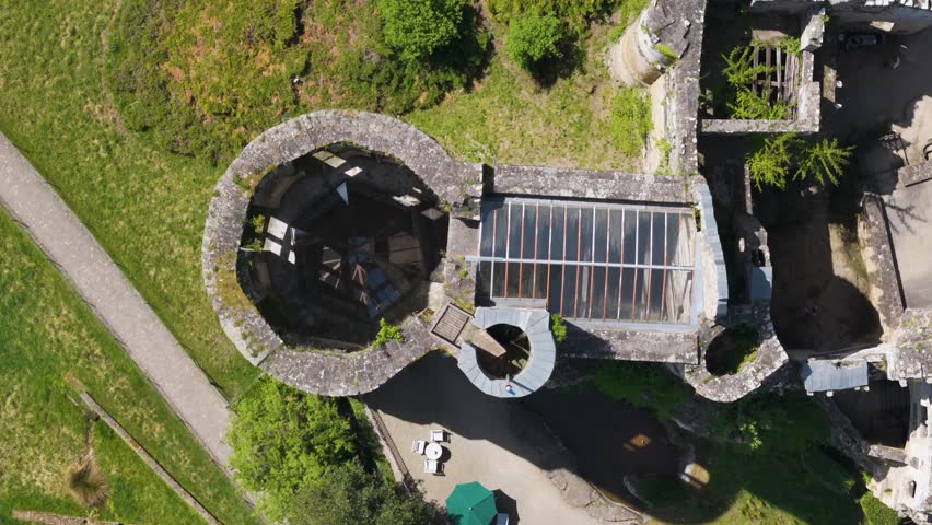 medieval castle beaufort outer walls ruins green gardens flag tall trees glass covered domes luxembourg overhead circling top drone shot les châteaux de