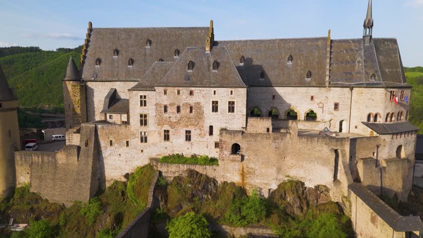 vianden castle chateau de historical site green hills cloudy sky flags walls homes cars complete to revealing left near right pans drone luxembourg panning