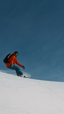 Snowboard rider riding down fresh powder during sunny day, Alpine scenery. Super slow motion at 1000 fps.