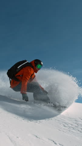 Snowboard rider riding down fresh powder during sunny day, Alpine scenery. Super slow motion at 1000 fps.