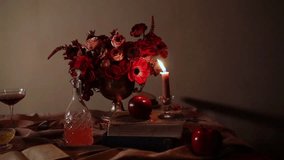 Moody still life with a lit candle, vintage books, red flowers, apples and glassware on a draped table. The candle flickers softly and then extinguishes, creating a dramatic, cinematic atmosphere. - Powered by Shutterstock - Get 15% off with code: PIKWIZARD15