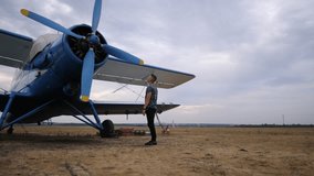 Pilot inspecting the blue biplane's propeller, showcasing the intricate details of the aircraft, while preparing for takeoff in an expansive open field, emphasizing the connection between man and - Powered by Shutterstock - Get 15% off with code: PIKWIZARD15