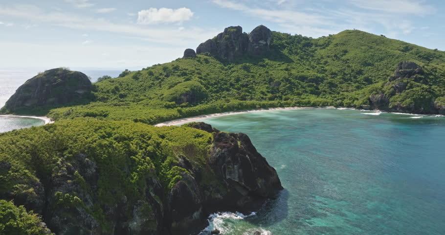 Fiji: Aerial drone view of secluded tropical bay with turquoise water, pristine sandy beach and lush green hills, perfect peaceful island paradise for travel and vacation. Aerial view drone flight