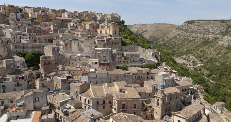Aerial view of a paved road through an Italian hilltop village nestled between the mountains. This is the historic center of Ragusa Ibla, Sicily, Italy.