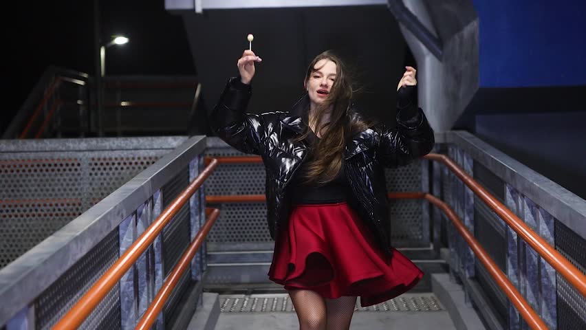 Beutiful young woman performing at night on an outside staircase at night