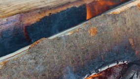 Macro view of burning wood, glowing embers, and smoke rising in natural daylight. - Powered by Shutterstock - Get 15% off with code: PIKWIZARD15