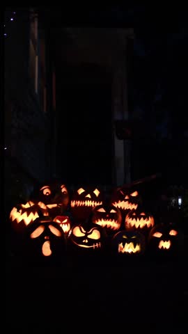 Halloween Jack O Lanterns at night in a glowing pile of pumpkins.