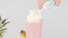 Hand applies whipped cream to pink fruit smoothie in glass, bright studio lighting, static shot - Powered by Shutterstock - Get 15% off with code: PIKWIZARD15