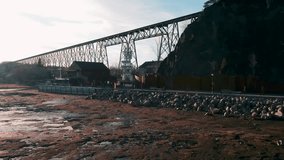 Steel truss bridge stands above rocky riverbank near Cap Rouge in Quebec City region as soft light highlights metal structure and rugged ground during slow moving cinematic drone view. - Powered by Shutterstock - Get 15% off with code: PIKWIZARD15