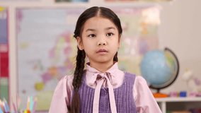Asian girl counts one, two, three on fingers in bright classroom, front-facing camera, natural lighting - Powered by Shutterstock - Get 15% off with code: PIKWIZARD15