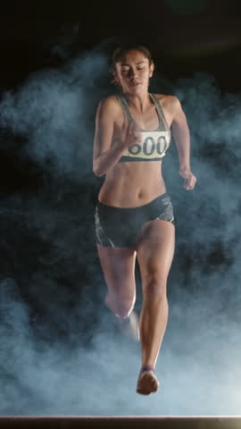 female athlete running from darkness through fog vertical slow motion fullHD symbol of strength motivation determination confidence victory mindset focus inspiration empowerment