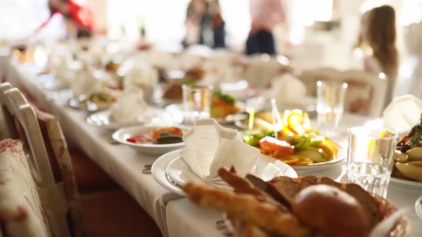 An elegant banquet table beautifully arranged with assorted snacks, appetizers, and festive décor, glowing in sunlight during a corporate or wedding celebration.