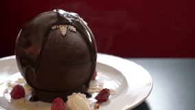 Gourmet chocolate sphere dessert melting under hot cocoa sauce, elegant plating with raspberries, whipped cream, almond flakes on plate in fine dining setting. sweet cake Snack food Restaurant Cafe - Powered by Shutterstock - Get 15% off with code: PIKWIZARD15