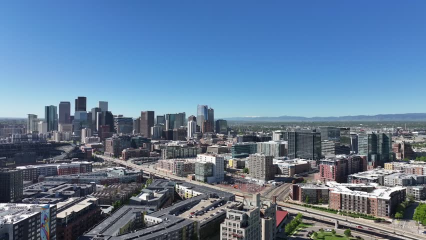 Aerial view of downtown Denver as the drone flies sideways with a clear blue sky above the city.