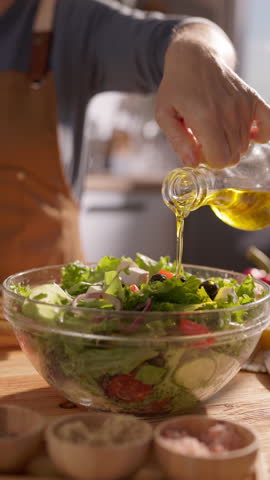 Clean eating lifestyle woman pouring olive oil on organic green salad slow motion vertical clip home chef cooking healthy fats concept mindful nutrition homemade
