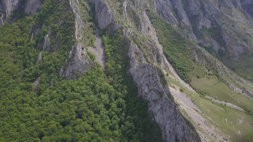 Aerial View Of Rocky Cliff Side, Rock Mountain With Green Vegetation And Valley