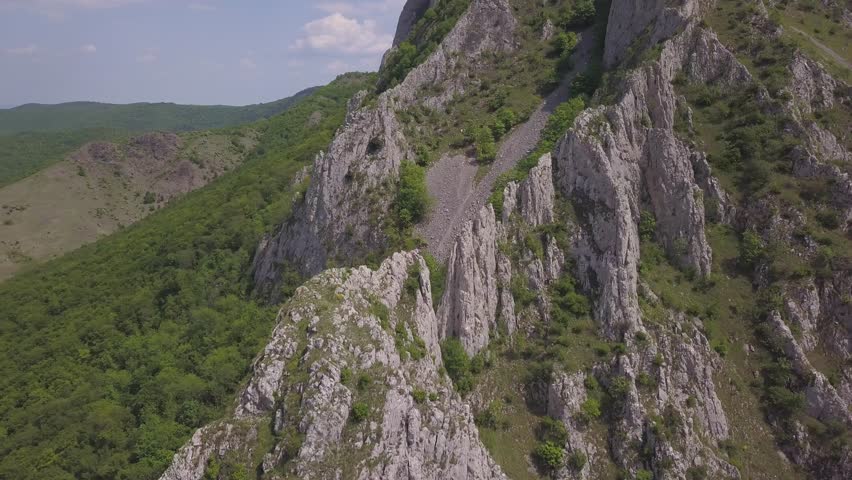 Aerial View Of Rocky Mountain Range With Rugged Rock Formations and Green Vegetation