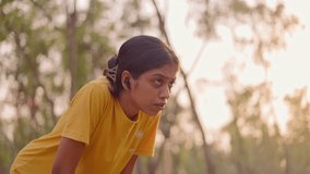 Tired athelete woman in sportswear relaxing and taking breath after workout session in a park during golden hour, symbolizing determination and wellness. - Powered by Shutterstock - Get 15% off with code: PIKWIZARD15