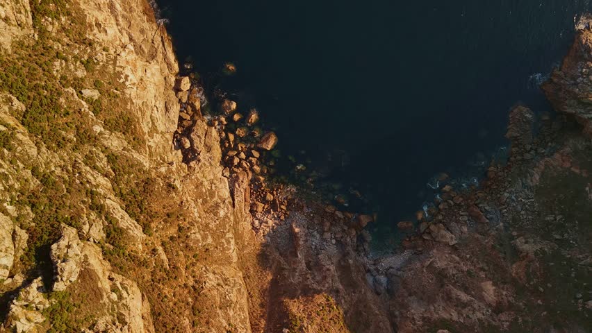 Rightward bird’s-eye drone glide over a Spanish cliff with land on one side and Atlantic ocean on the other near the Camino de Santiago. Smooth coastal movement with rugged textures below.