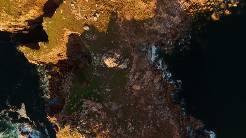 Smooth drone glide over a narrow Spanish mountain cliff with ocean on both sides near the Camino de Santiago. Cinematic aerial movement revealing rugged rocks and dramatic Atlantic scenery.