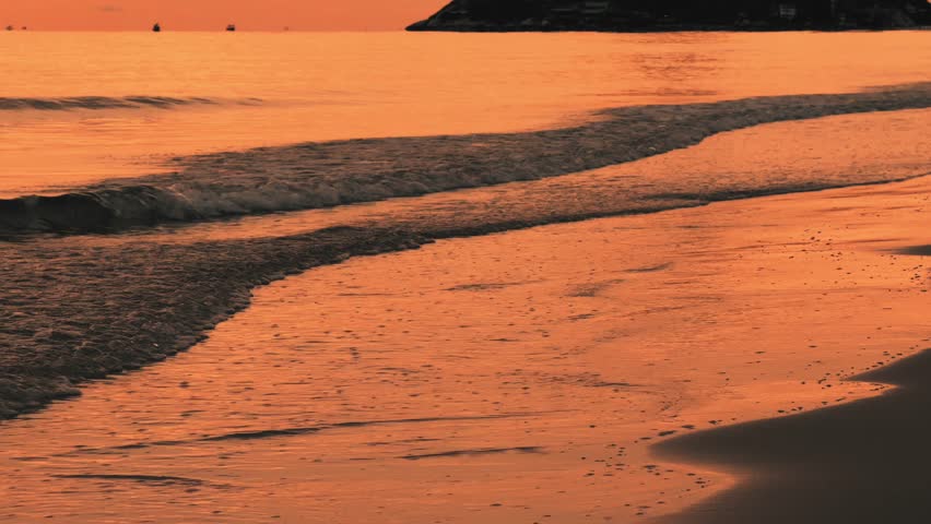 Golden sunset reflecting on wet sand with gentle waves at the shoreline