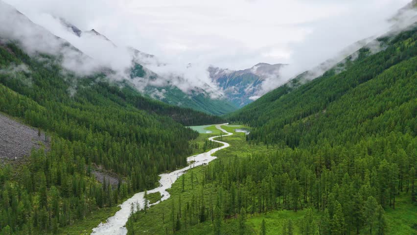 drone flight over the mountain river Shavla, cloud peaks in the clouds, Altai mountains
