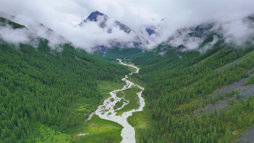 drone flight over the mountain river Shavla, cloud peaks in the clouds, Altai mountains
