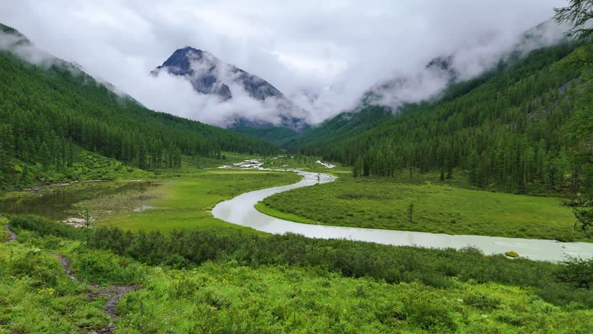 drone flight over the mountain river Shavla, cloud peaks in the clouds, Altai mountains
